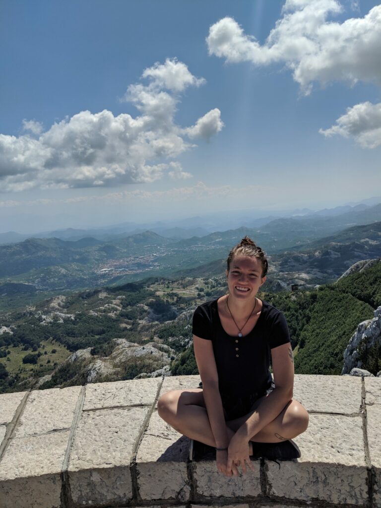 Justyn sitting at a viewpoint overlooking the mountains of Montenegro.