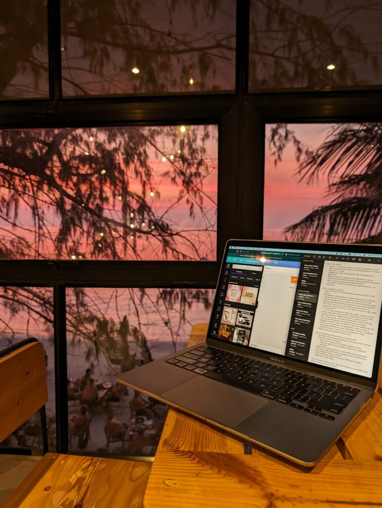 A beautiful pink sunset sky out a window over the beach in Koh Tao - featuring my laptop.