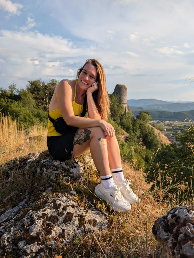 Justyn sitting on a rock overlooking a castle in Italy.